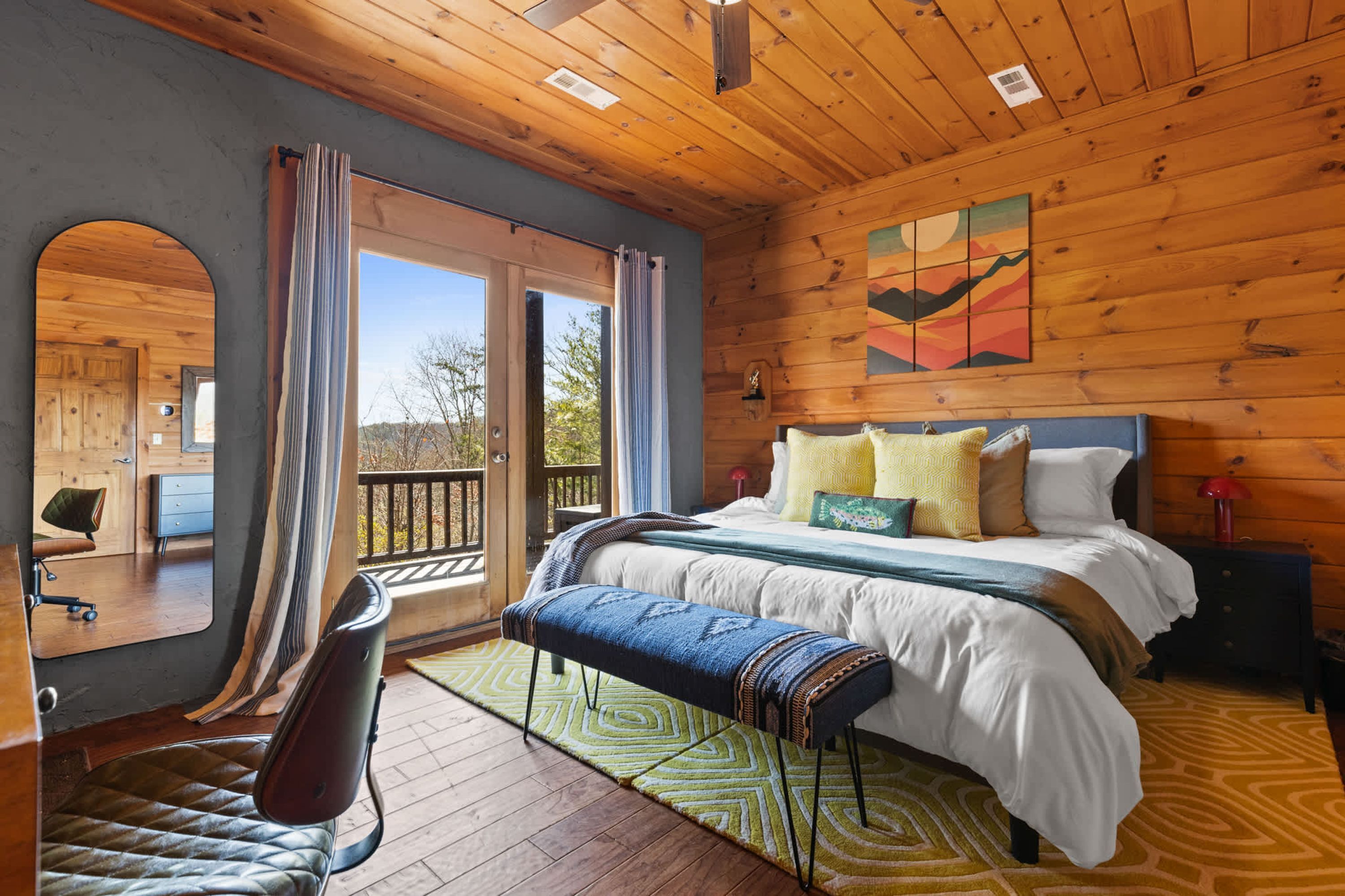 A wooden cabin bedroom with a bed, bench, and a view of the outdoors.