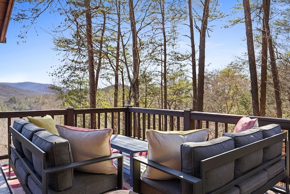 Una terraza con asientos al aire libre y vistas a un bosque y montañas.