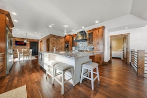 A modern kitchen with a central island, bar stools, and a visible Netflix sign. - Lakefront Oasis Private Dock Pool Sleeps 20 (Sunrise Beach)