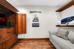 A living room with a wooden cabinet, a television, a couch, and a wall with a poster and a sign. - Lakefront Oasis Private Dock Pool Sleeps 20 (Sunrise Beach)