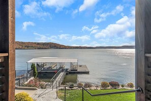 Ein Ufergrundstück mit Anlegesteg, überdachter Sitzgelegenheit und Blick auf einen See und ferne Hügel.