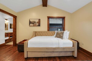 Un dormitorio con una cama grande, una ventana con persianas, un cuadro en la pared y suelo de madera.