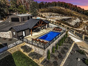 Una propiedad con piscina, mobiliario exterior y un muro de contención de piedra.