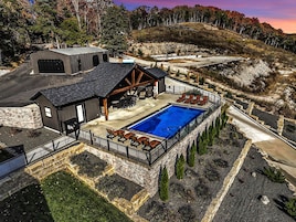 Una propiedad con piscina, mobiliario exterior y un muro de contención de piedra.
