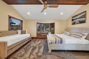 Ein Schlafzimmer mit einem Bett, einem Schlafsofa, einem Deckenventilator und einem Fenster mit Jalousien.