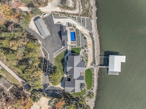 An aerial view of a property with a swimming pool, a parking area, and a dock extending into a body of water. - Lakefront Oasis Private Dock Pool Sleeps 20 (Sunrise Beach)