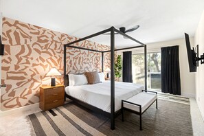 Ein Bett mit Baldachin, eine Bank, ein Nachttisch, eine Lampe und eine Wand mit Muster.