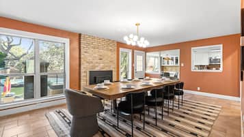 A modern kitchen with white cabinets, a built-in oven, and a dining area with a long wooden table and black chairs.
