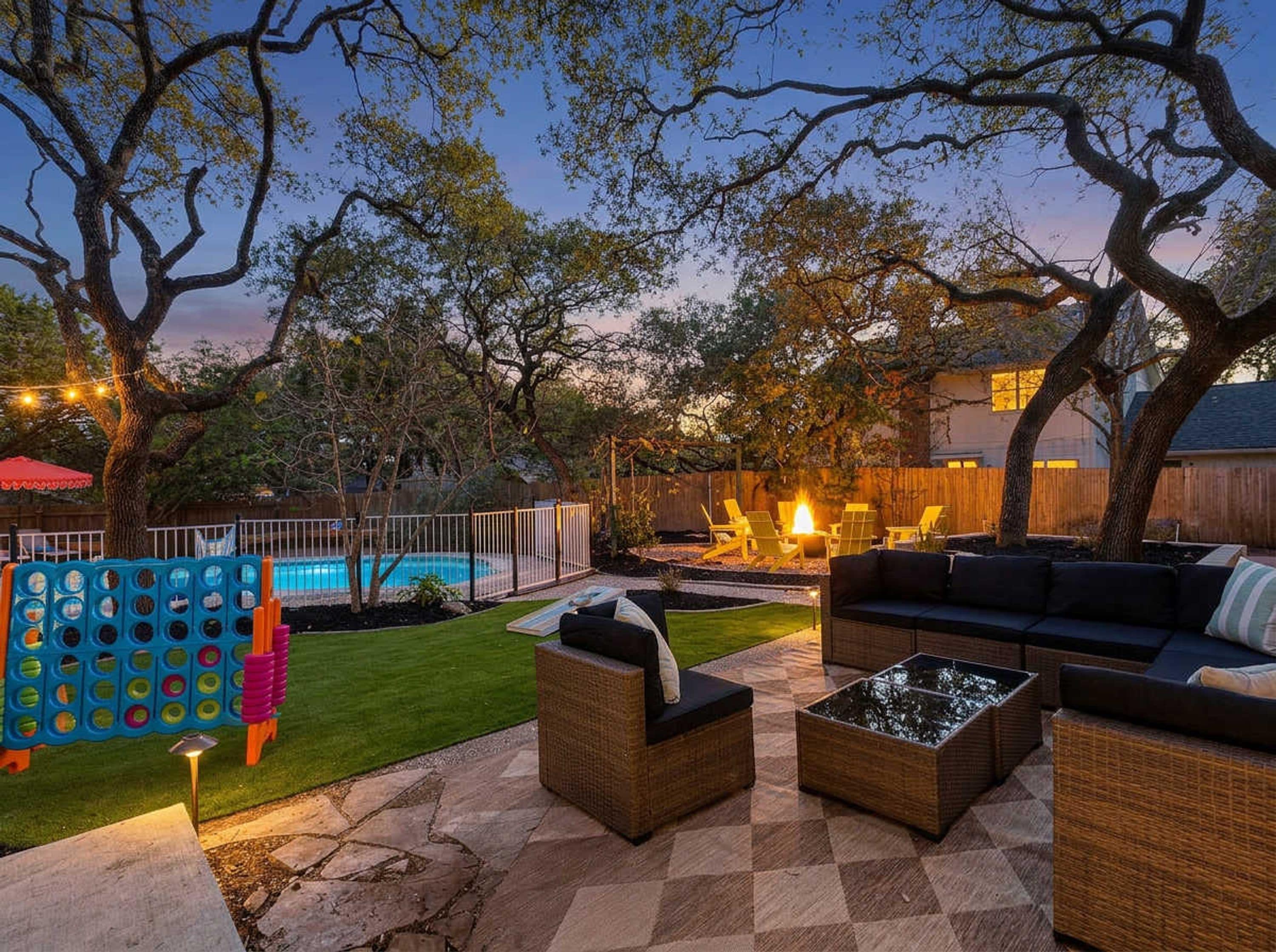 Un jardin avec une piscine, du mobilier d’extérieur et un foyer.