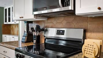 A kitchen with a stainless steel stove, a microwave, and a blender on the counter.