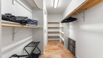 A narrow hallway with shelving units on both sides, a radiator on the right, and a door at the end.