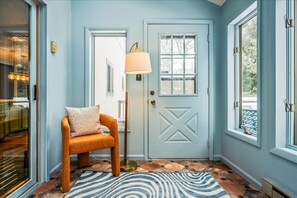 A room with a light blue door, a patterned rug, a chair, and a floor lamp. - NEW Movie Theater Game Room Amenity Access (Tobyhanna)