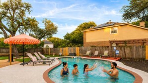 A swimming pool with a brick border, surrounded by lounge chairs and an umbrella. - Austin Encore Pool Hot Tub Putt-putt (Austin)