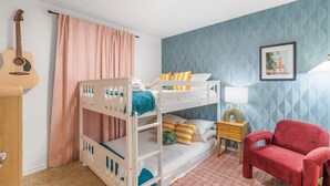 A room with bunk beds, a guitar, a red chair, and a framed picture on the wall. - Austin Encore Pool Hot Tub Putt-putt (Austin)