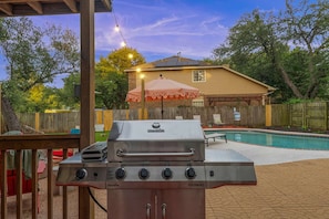 A backyard with a barbecue grill, a swimming pool, and a covered patio area. - Austin Encore Pool Hot Tub Putt-putt (Austin)