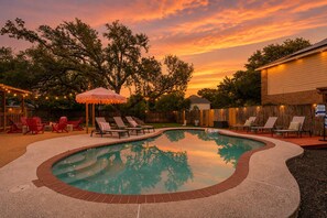 A swimming pool with a curved edge, surrounded by lounge chairs and a wooden deck. - Austin Encore Pool Hot Tub Putt-putt (Austin)