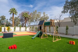 Ein Spielplatz mit Basketballkorb, Rutsche und Klettergerüst.
