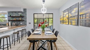 Uma área de jantar moderna com uma mesa de madeira, cadeiras pretas e um vaso de tulipas vermelhas.