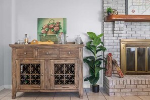 Um armário de madeira com portas de vidro, uma pintura de flores e um vaso com planta.
