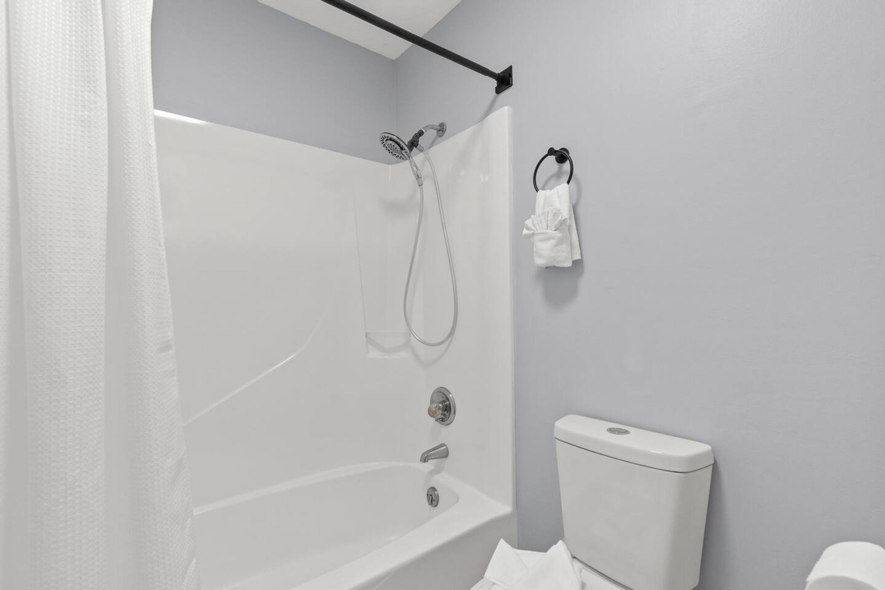 A bathroom with a shower, toilet, and towel rack.