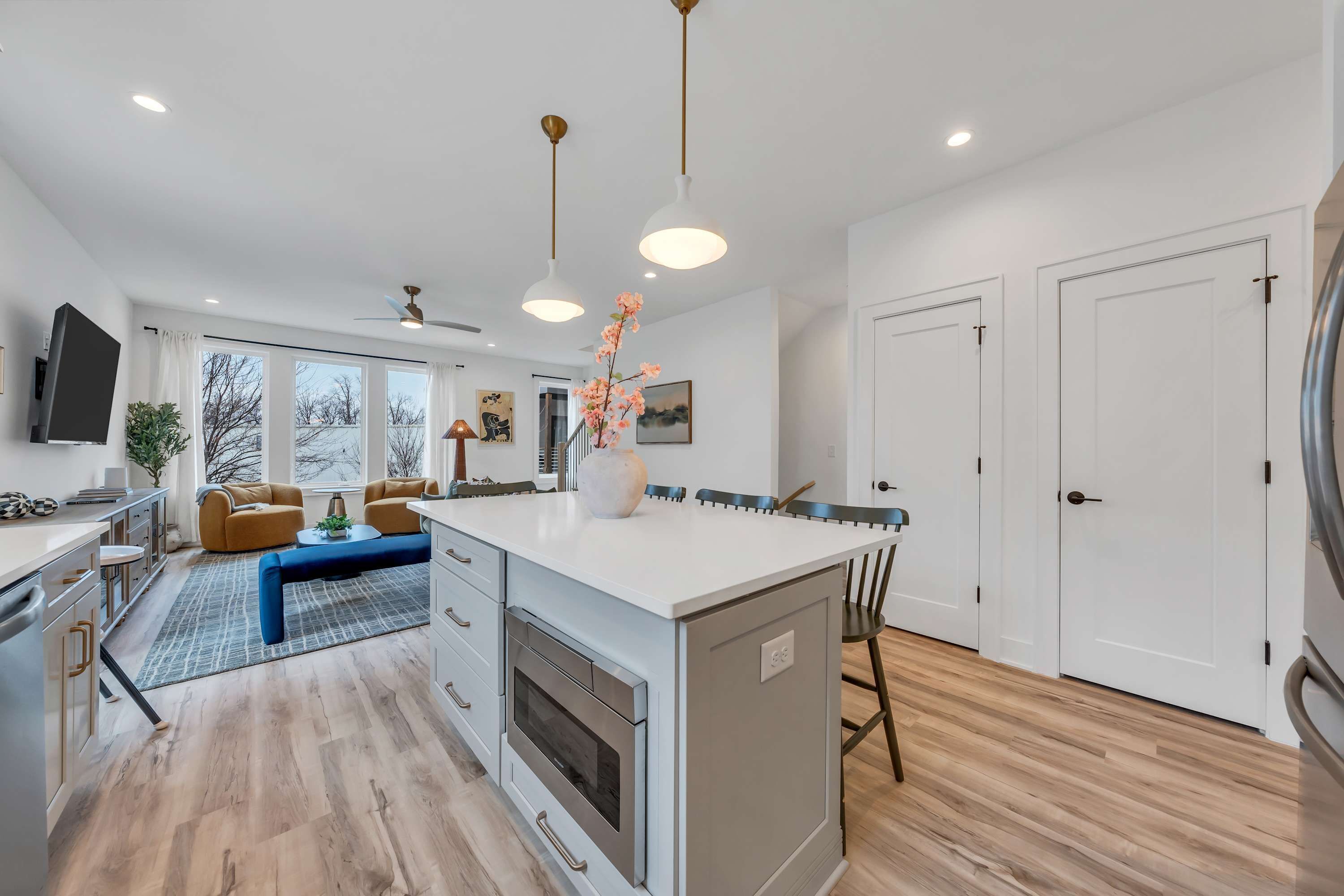 A modern kitchen with a central island, built-in oven, and a dining area with a bench.