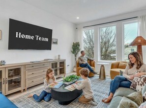 Uma sala de estar com televisão exibindo 'Home Team', um sofá, uma mesa de centro e um armário.