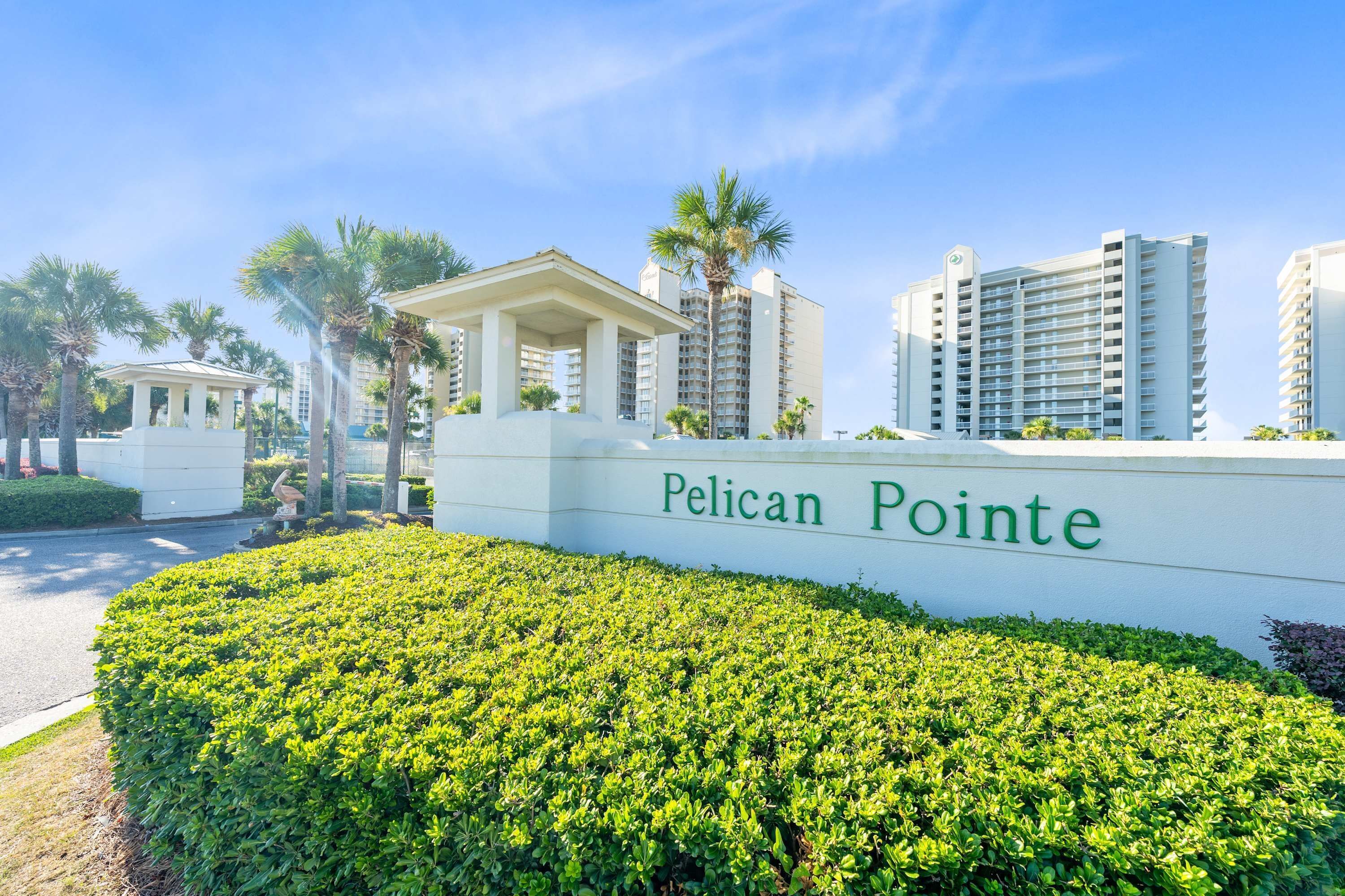 Une enseigne indiquant l’emplacement de « Pelican Pointe », avec un beau parterre de haies bien entretenu au premier plan.