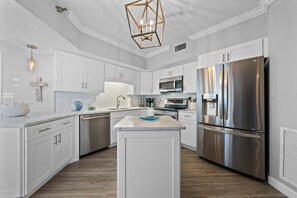 A modern kitchen with white cabinetry, stainless steel appliances, and a central island. - Beach Front 7th Floor Views Pools Hot Tub (Orange Beach)
