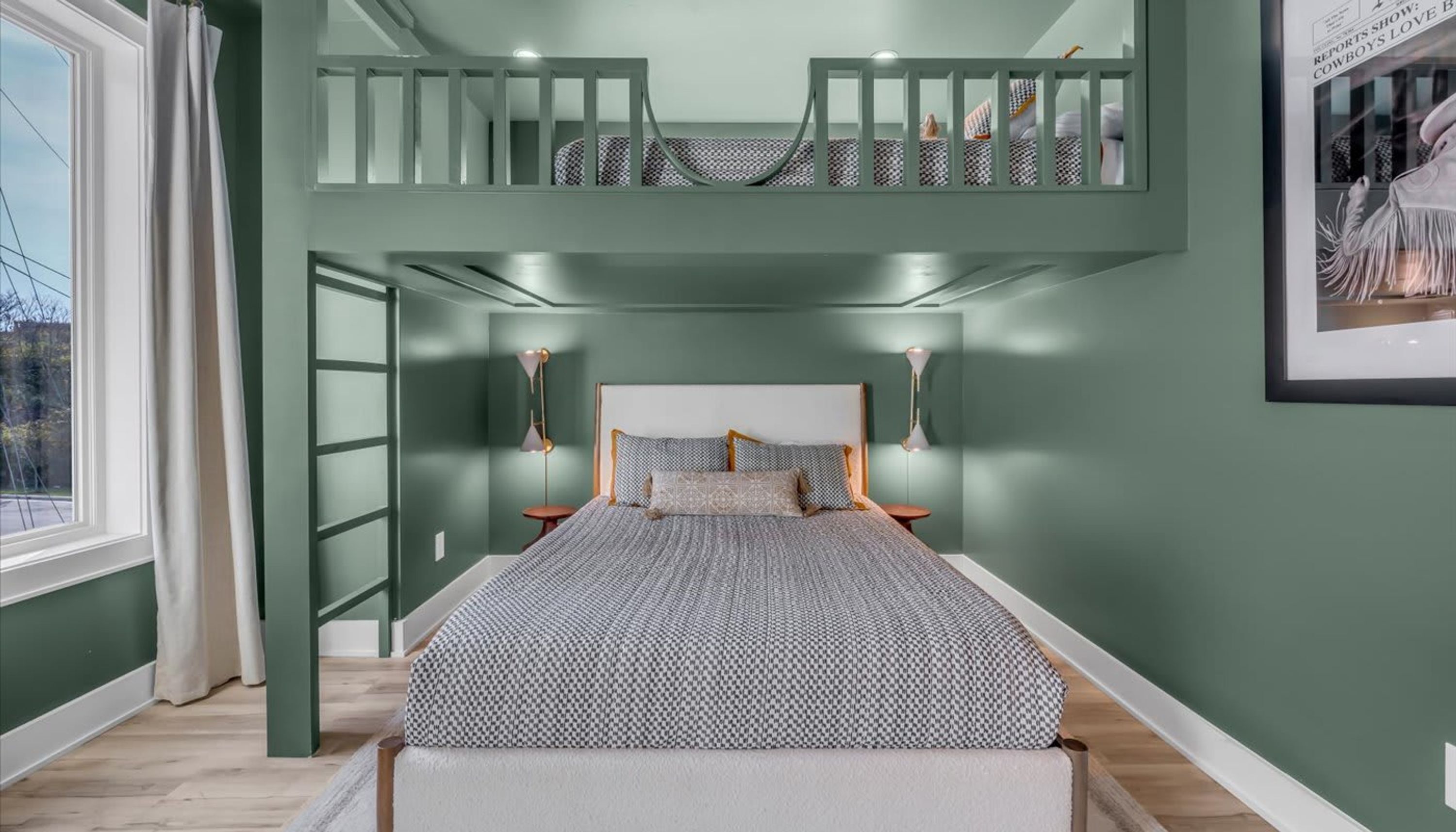 A bedroom with a bunk bed, a large window, and a framed picture on the wall.