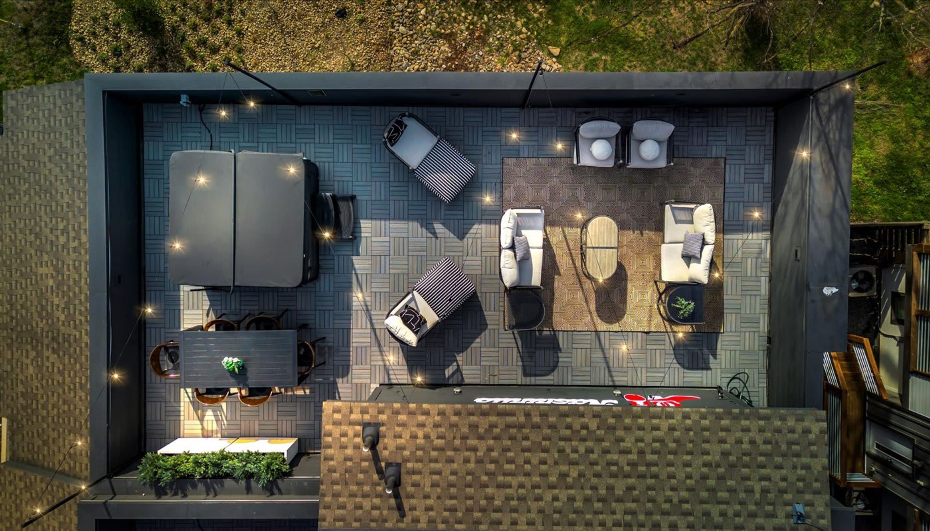Een terras buiten met een zithoek, een tafel en een kleine tuin.