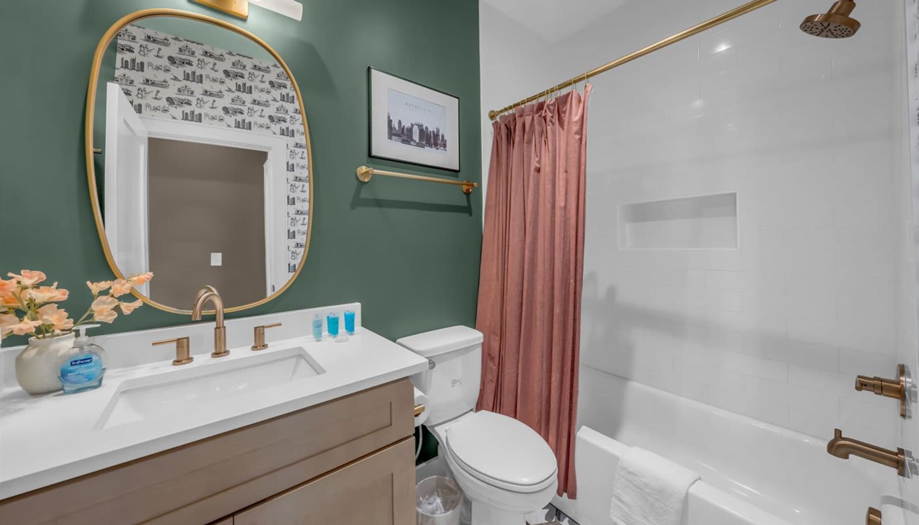 A bathroom with a white sink, a mirror with a decorative frame, a toilet, and a shower with a curtain.