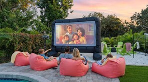 Eine Familien beim Film schauen auf einer Leinwand im Freien.