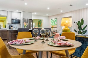 Un comedor moderno con una mesa redonda, sillas amarillas y una cocina al fondo.