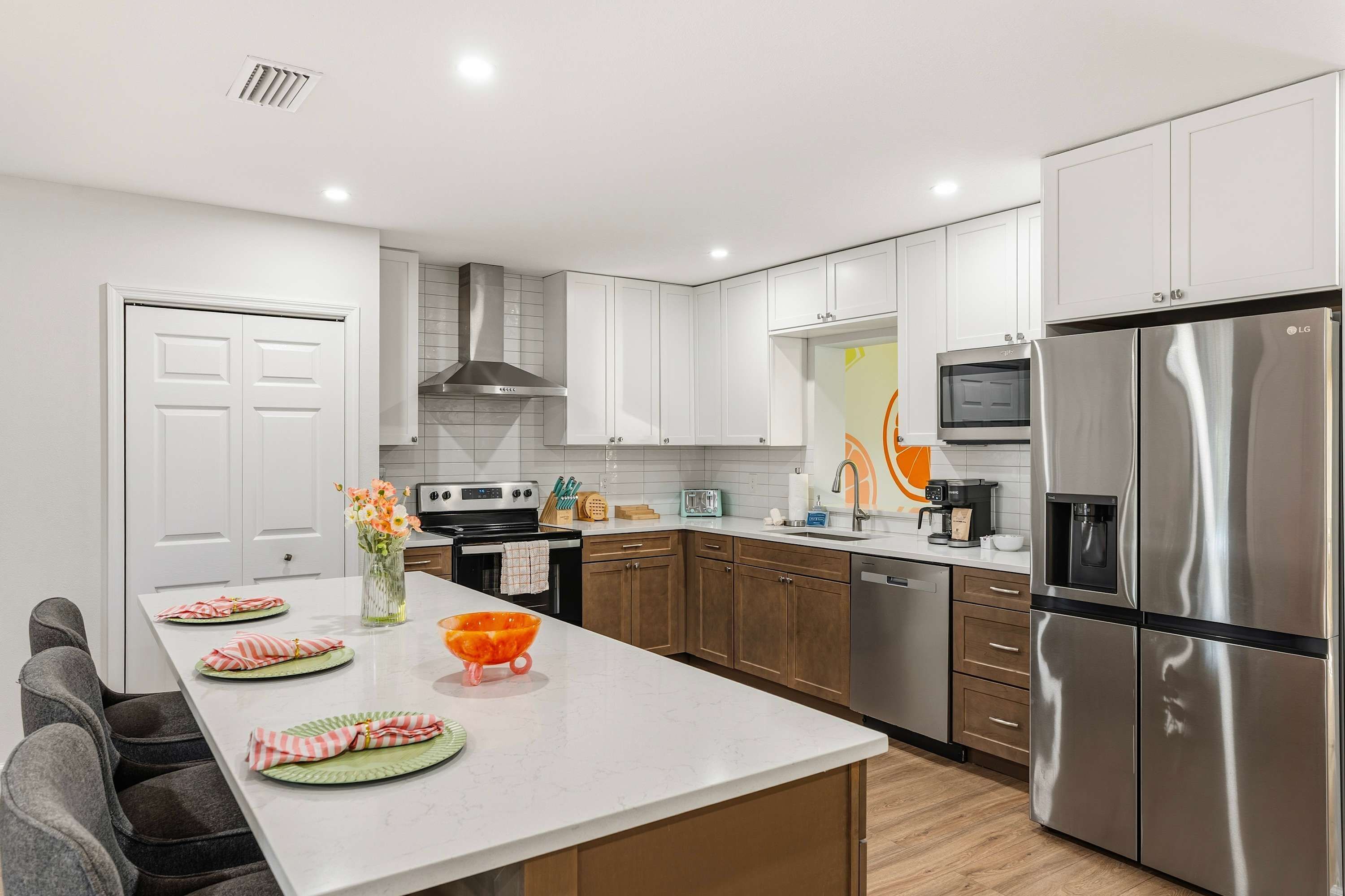 A modern kitchen with white cabinetry, stainless steel appliances, and a central island with a vase of flowers.