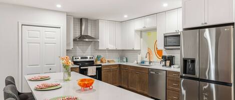 A modern kitchen with white cabinetry, stainless steel appliances, and a central island with a vase of flowers.