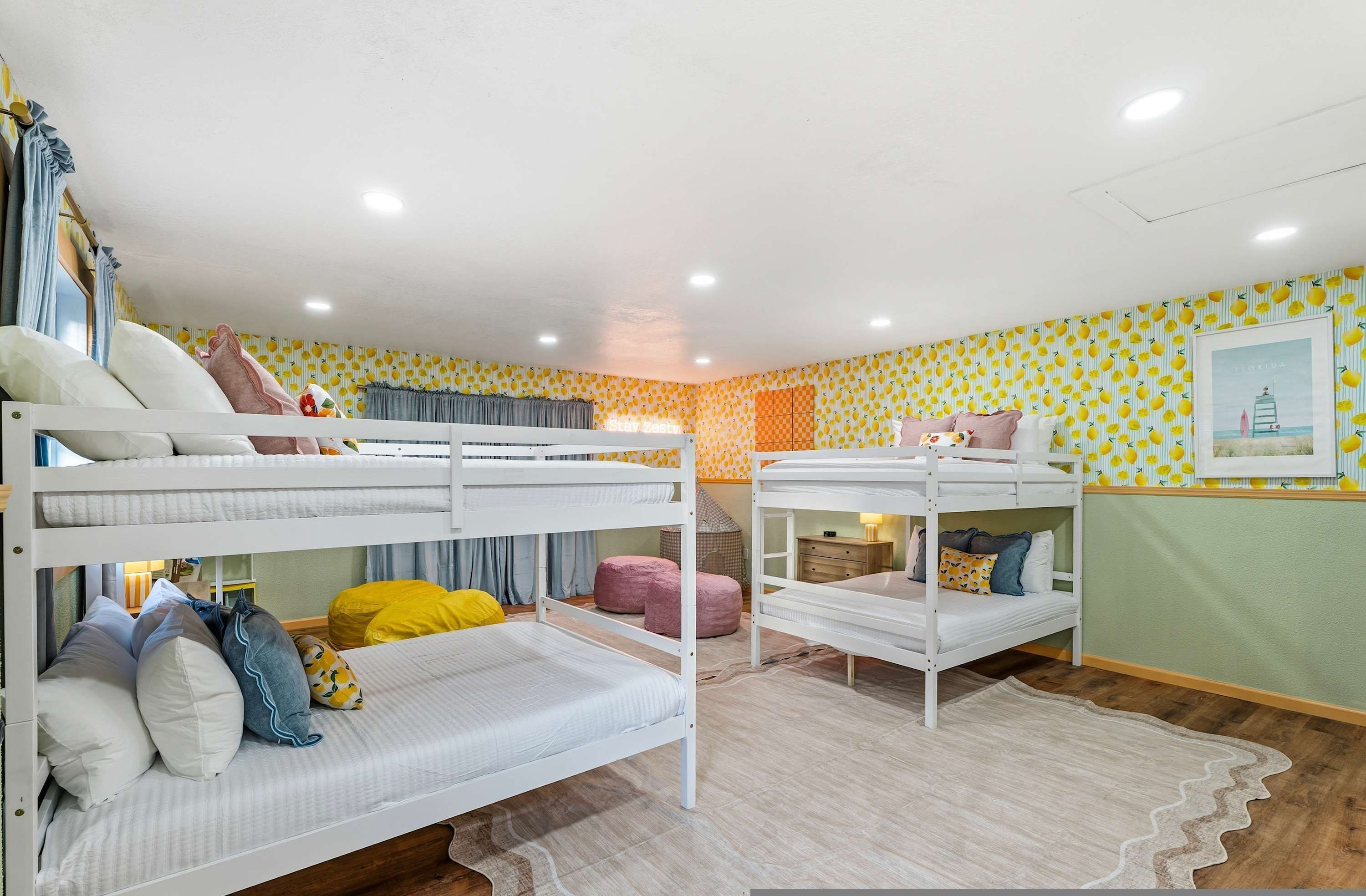 A bunk bed room with two beds, a small table, and a wall with a lemon pattern.