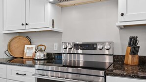 Una cocina moderna con electrodomésticos de acero inoxidable, utensilios de madera y un bloque para cuchillos.