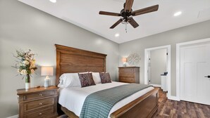 Un dormitorio con cama de madera, mesitas de noche, ventilador de techo y lámpara de noche.