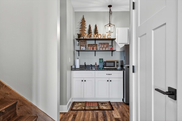 A kitchen with white cabinets, a microwave, and a coffee maker on the counter.