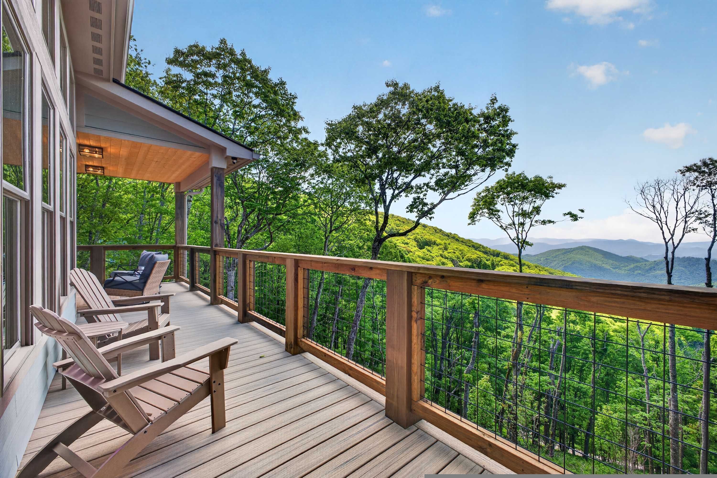 Eine Holzterrasse mit Sitzgelegenheiten im Freien, mit Blick auf eine bewaldete Landschaft und Berge in der Ferne.