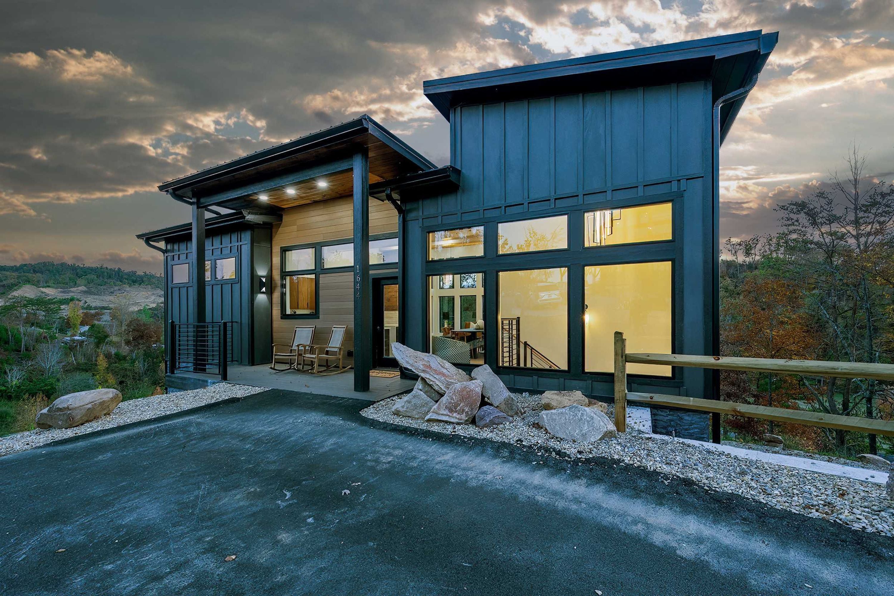 A modern building with large windows and a stone facade, located in a natural setting.