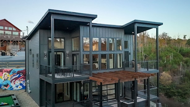 A modern two-story house with a balcony and a covered outdoor seating area. - Luxury 3 Br Cabin Indoor Pool Hot Tub Fire Pit (Sevierville)