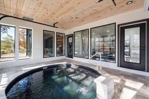 A modern indoor pool area with a wooden ceiling, large windows, and a clear view of the outdoors. - Luxury 3 Br Cabin Indoor Pool Hot Tub Fire Pit (Sevierville)