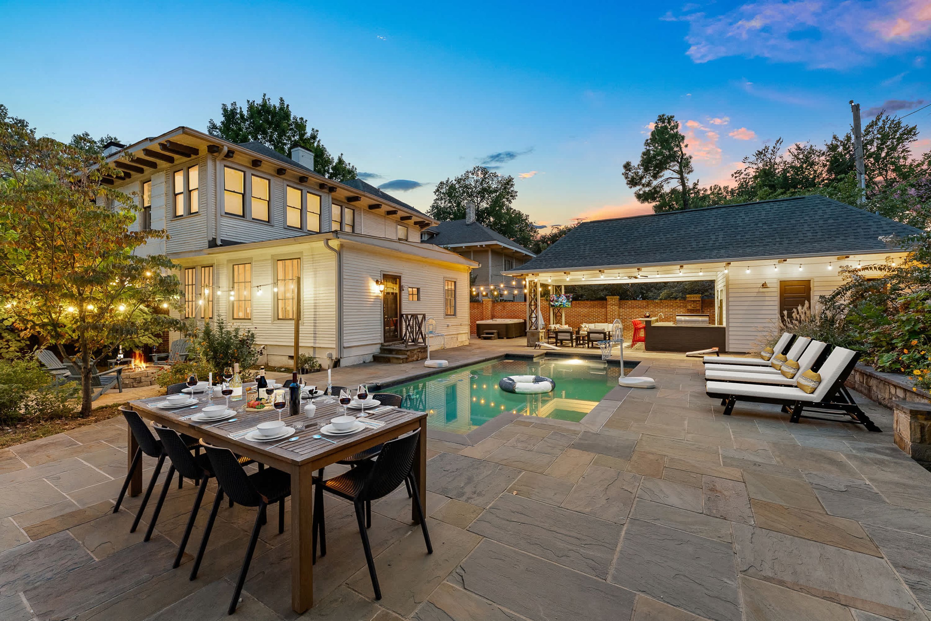 A backyard with a pool, dining area, and outdoor seating.