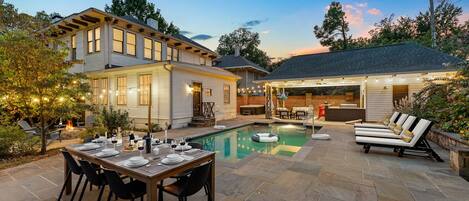 A backyard with a pool, dining area, and outdoor seating.