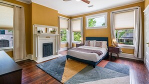 A bedroom with a fireplace, a bed, a ceiling fan, and large windows with curtains. - 6BR Home Private Pool Spa Games Gazebo (Memphis)