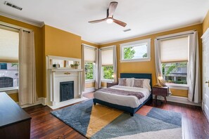 A bedroom with a fireplace, a bed, a ceiling fan, and large windows with curtains. - 6BR Home Private Pool Spa Games Gazebo (Memphis)