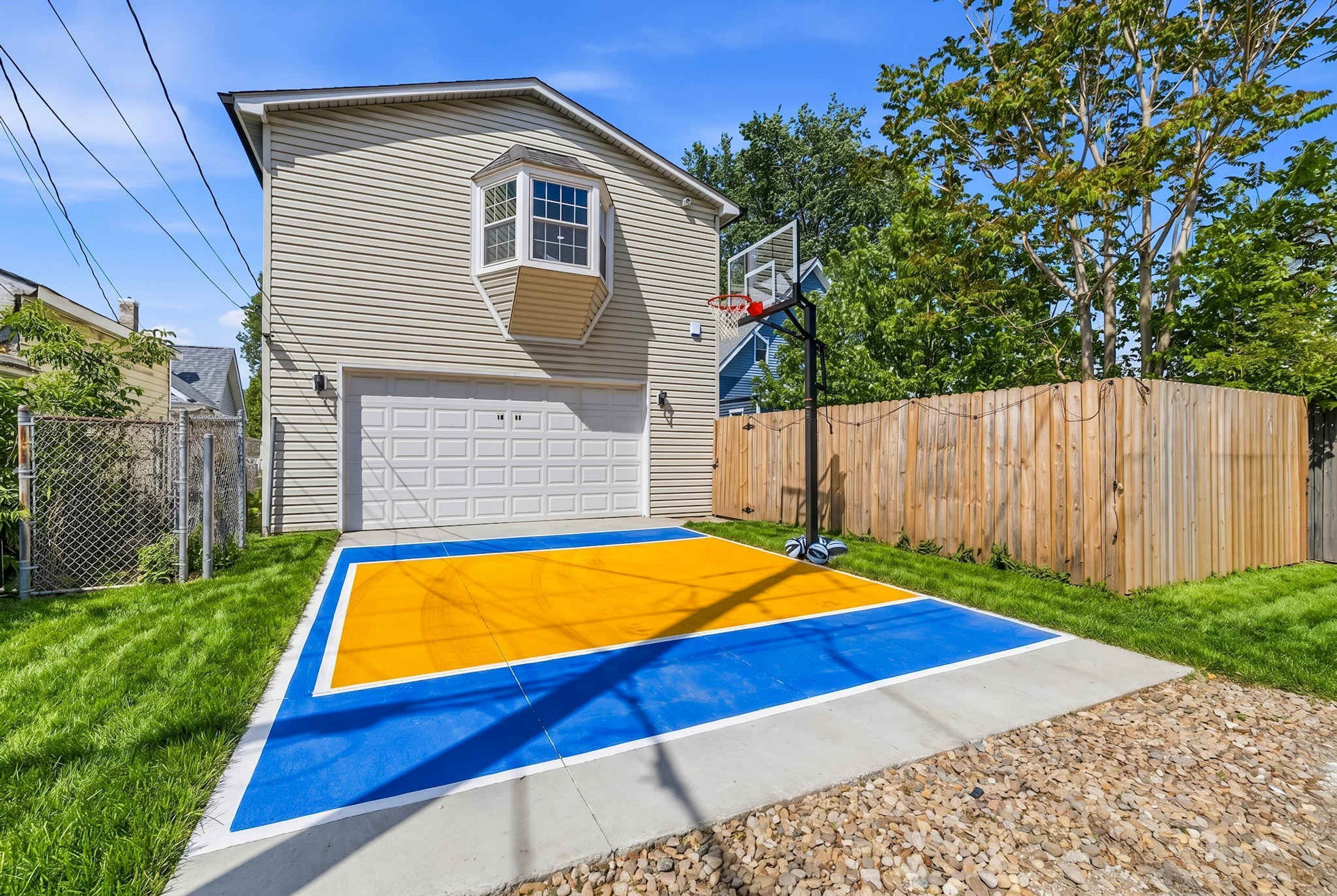 Ein Wohnhaus mit Garage, Basketballplatz und Holzzaun.