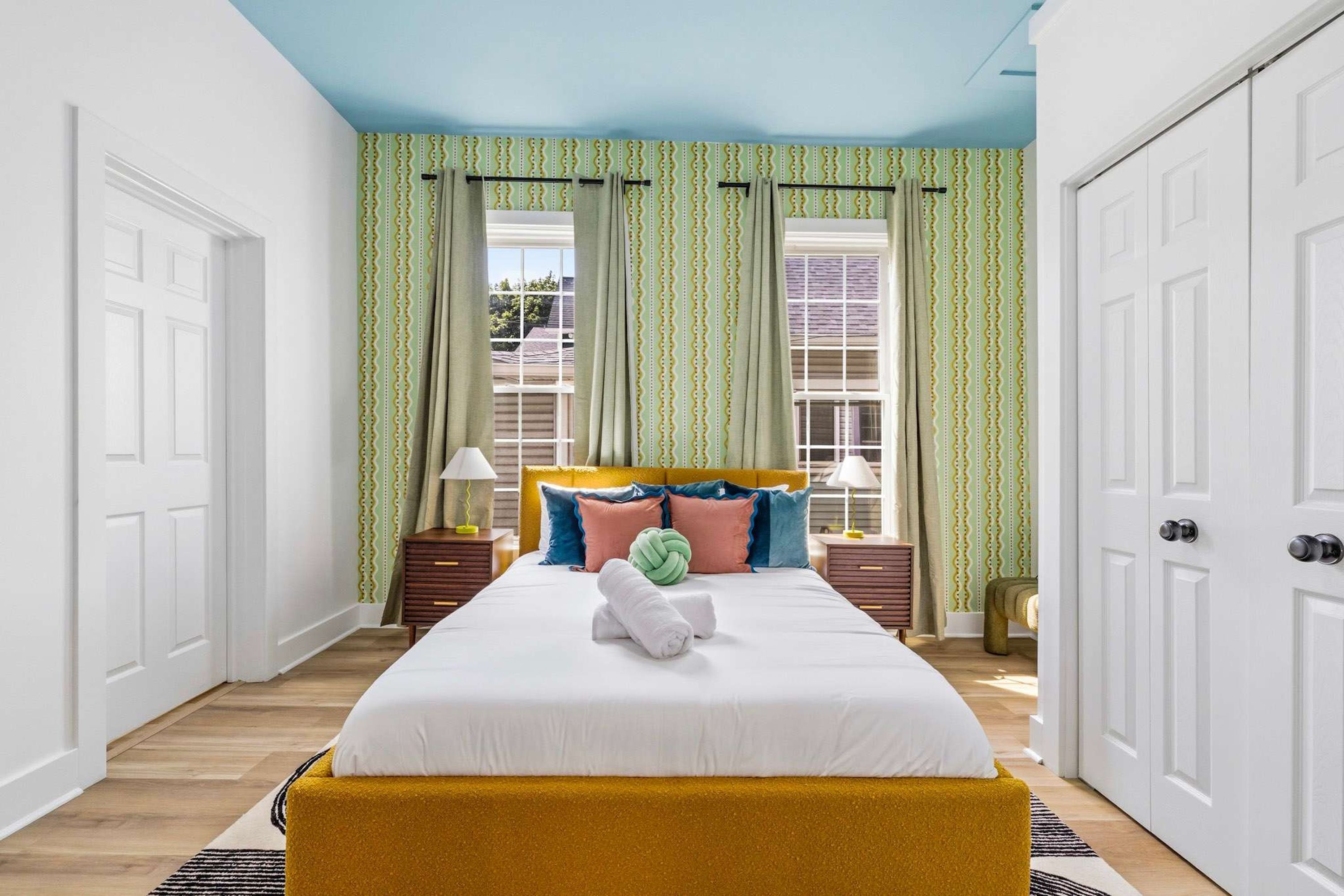 Ein Hotelzimmer mit Bett, Vorhängen, Nachttisch und Lampe.