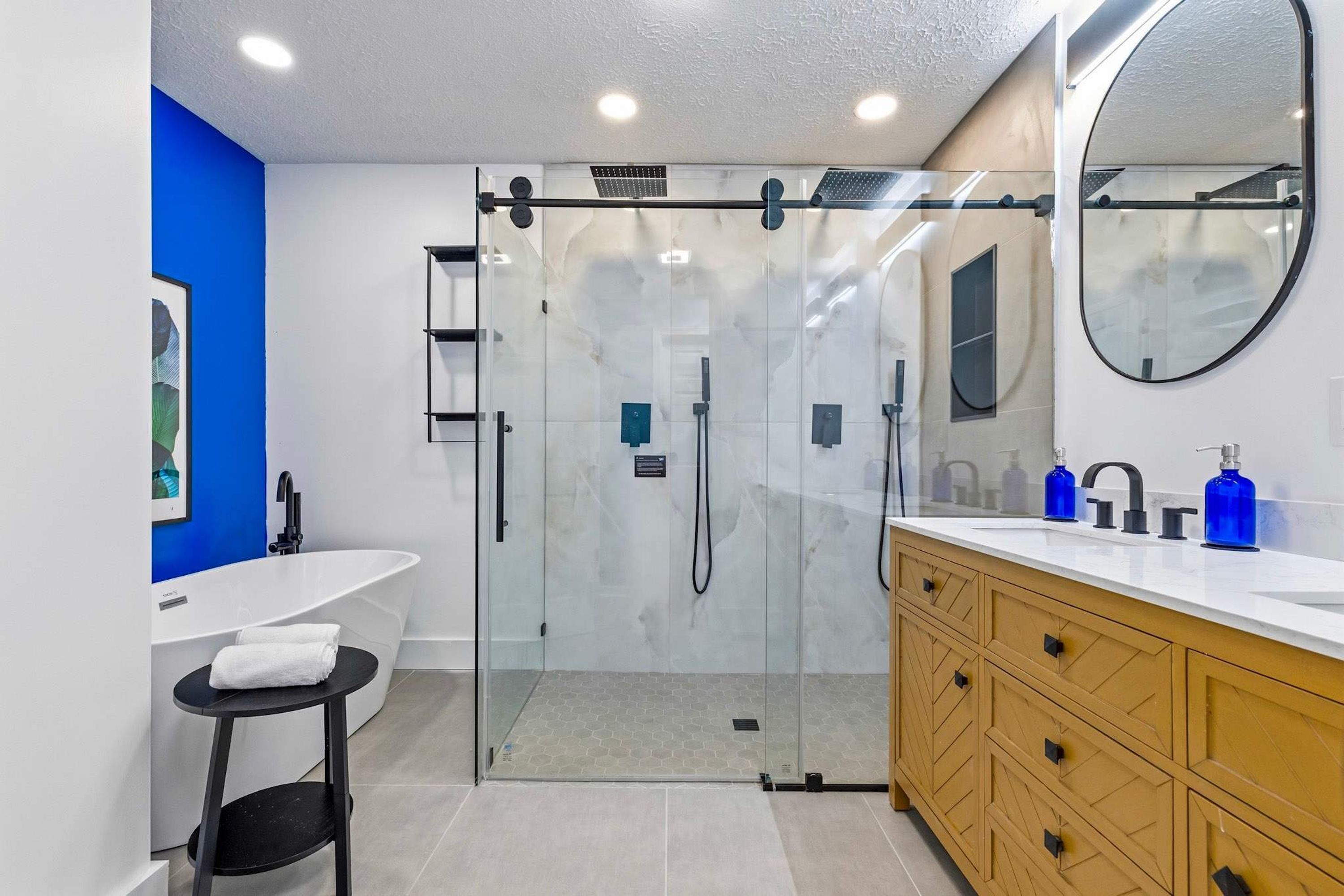 A modern bathroom with a glass shower enclosure, a white sink, and a wooden vanity.